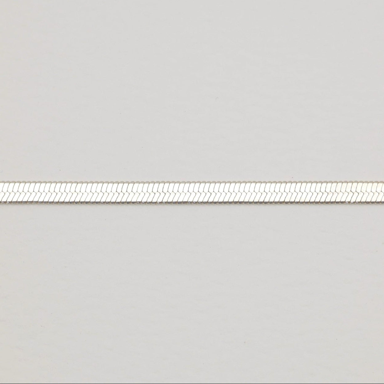 Flat herringbone bracelet in polished sterling silver with lobster clasp.