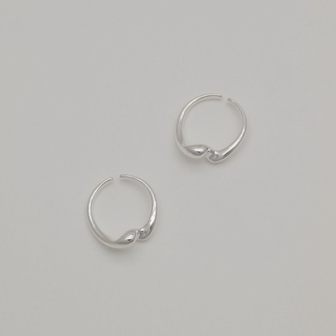 Sterling silver duo rings with soft sculptural curves and open adjustable bands, displayed on a neutral background.