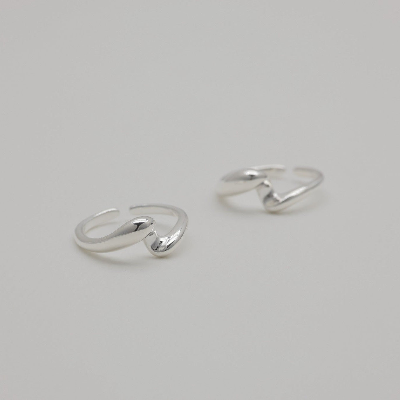 Sterling silver duo rings with soft sculptural curves and open adjustable bands, displayed on a neutral background.