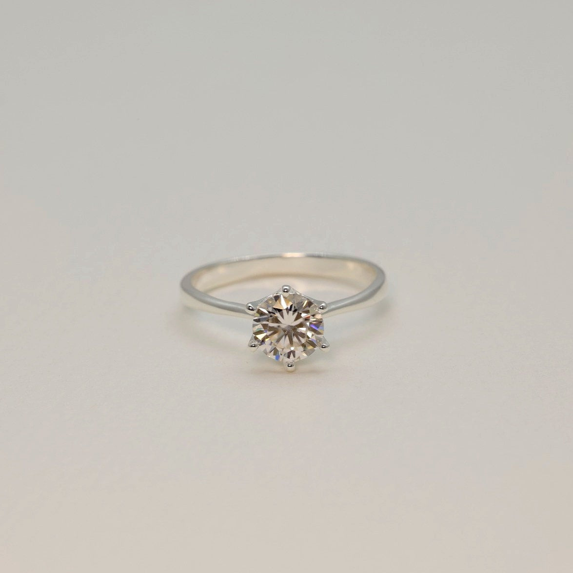 Moissanite solitaire ring in sterling silver photographed on soft white background