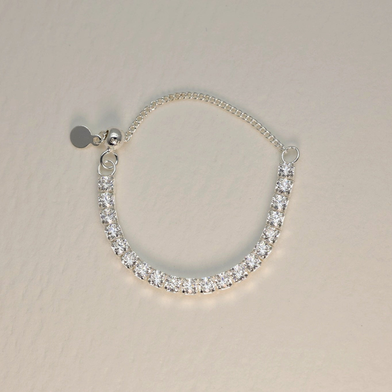 Silver bracelet with clear stones on a beige background