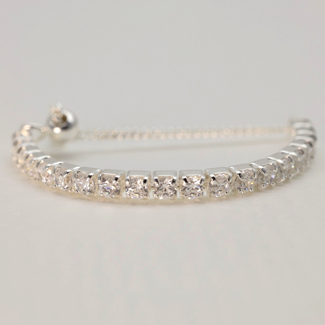 Silver bracelet with clear stones on a light gray background