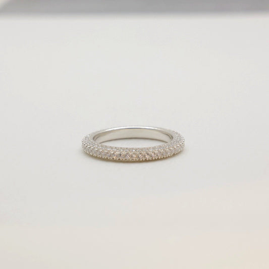 Angled view of the eternity ring resting on a soft surface with subtle light reflections.