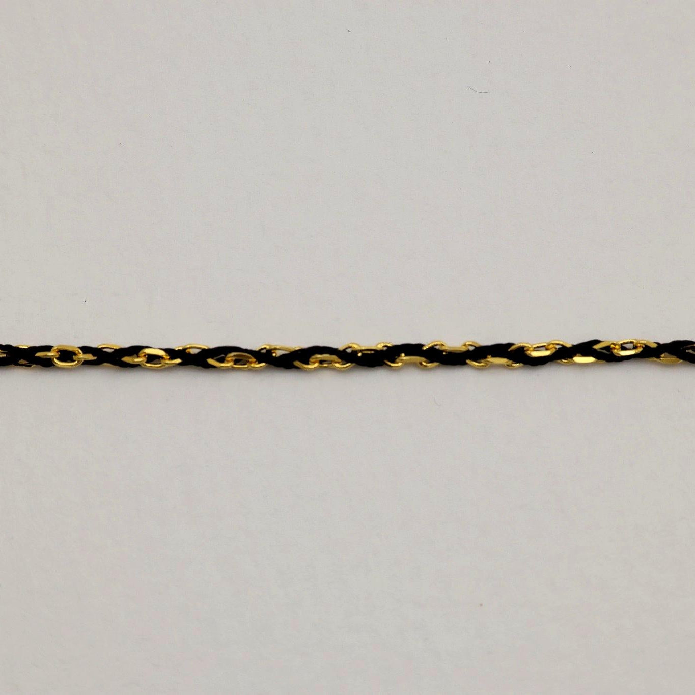 Gold vermeil and black rope chain bracelet close-up showing polished twisted design.

