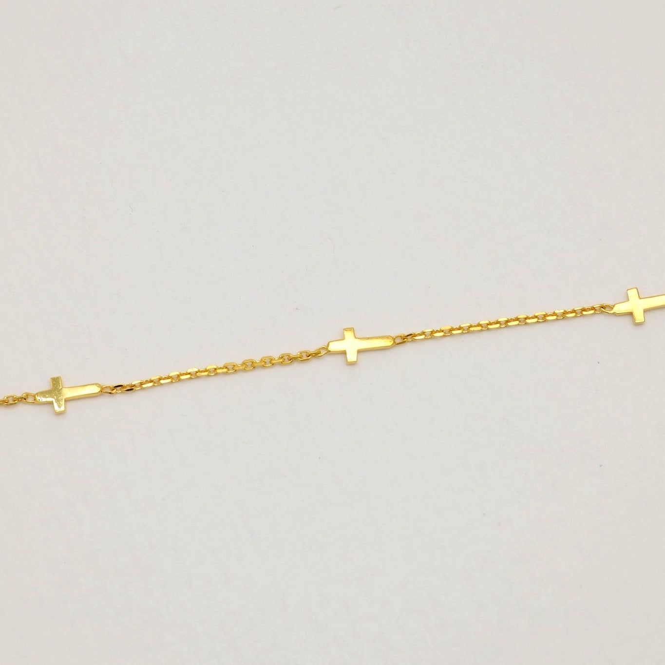 Close-up of cross details on a fine gold vermeil chain

