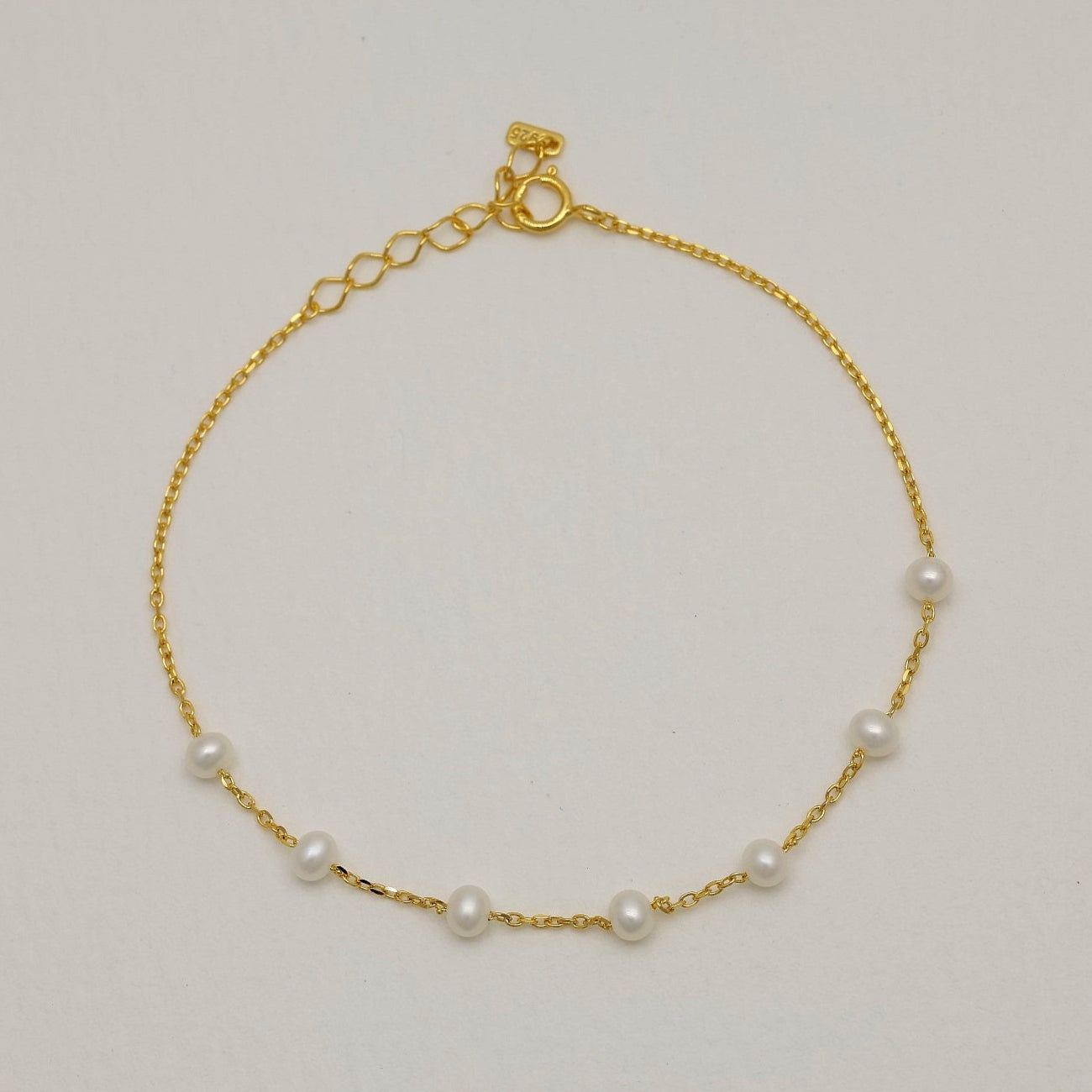 Full circular view of a gold vermeil bracelet with evenly spaced freshwater pearls and a spring clasp with extender.

