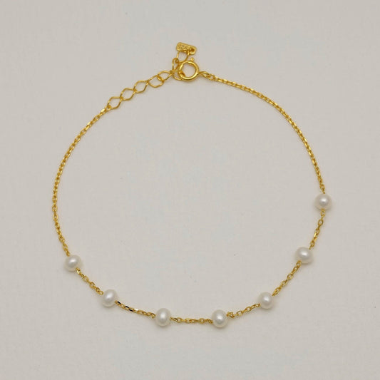 Full circular view of a gold vermeil bracelet with evenly spaced freshwater pearls and a spring clasp with extender.

