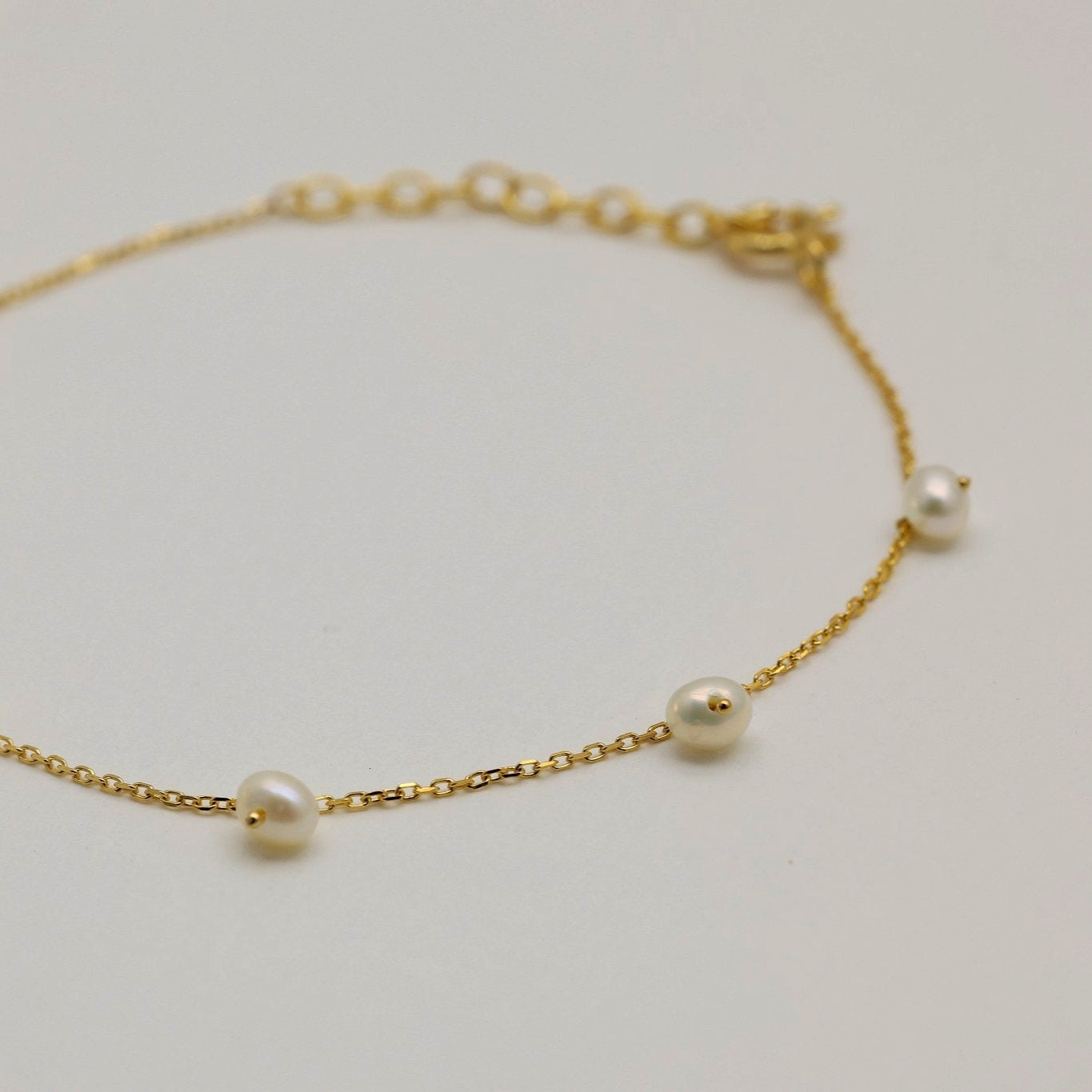 Flatlay showing gold vermeil bracelet with scattered freshwater pearls


