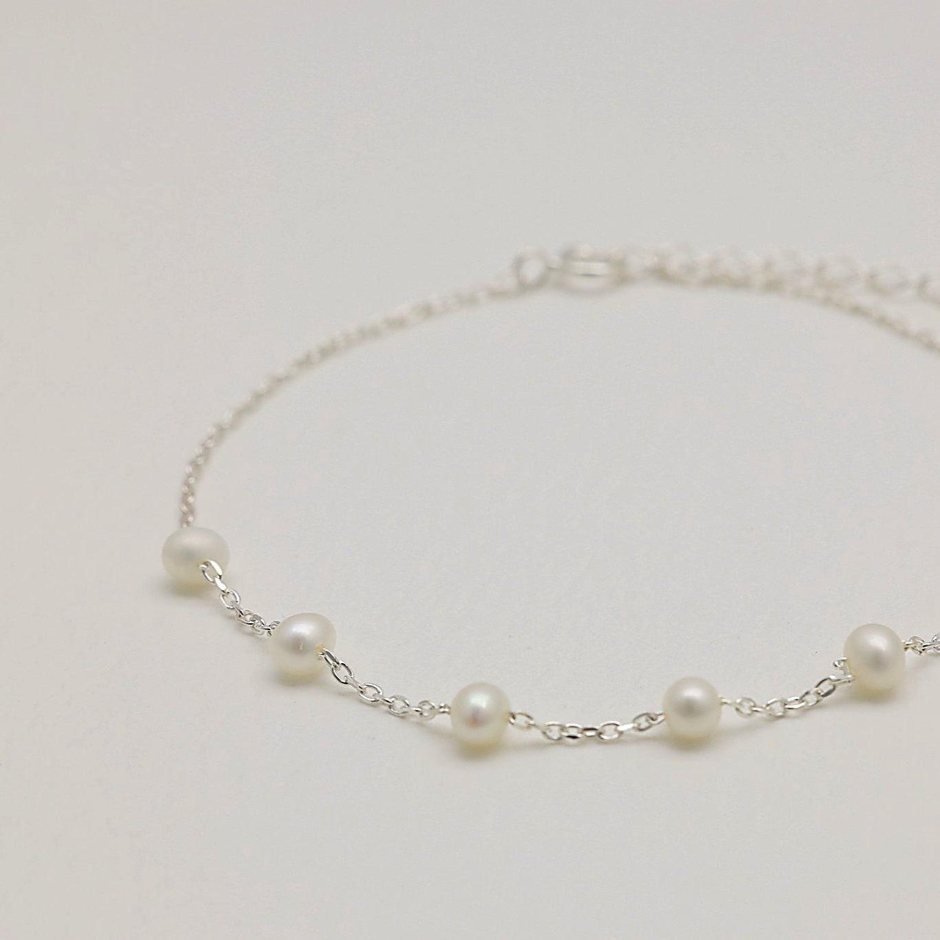 Théa bracelet shown with pearls spaced along silver chain
