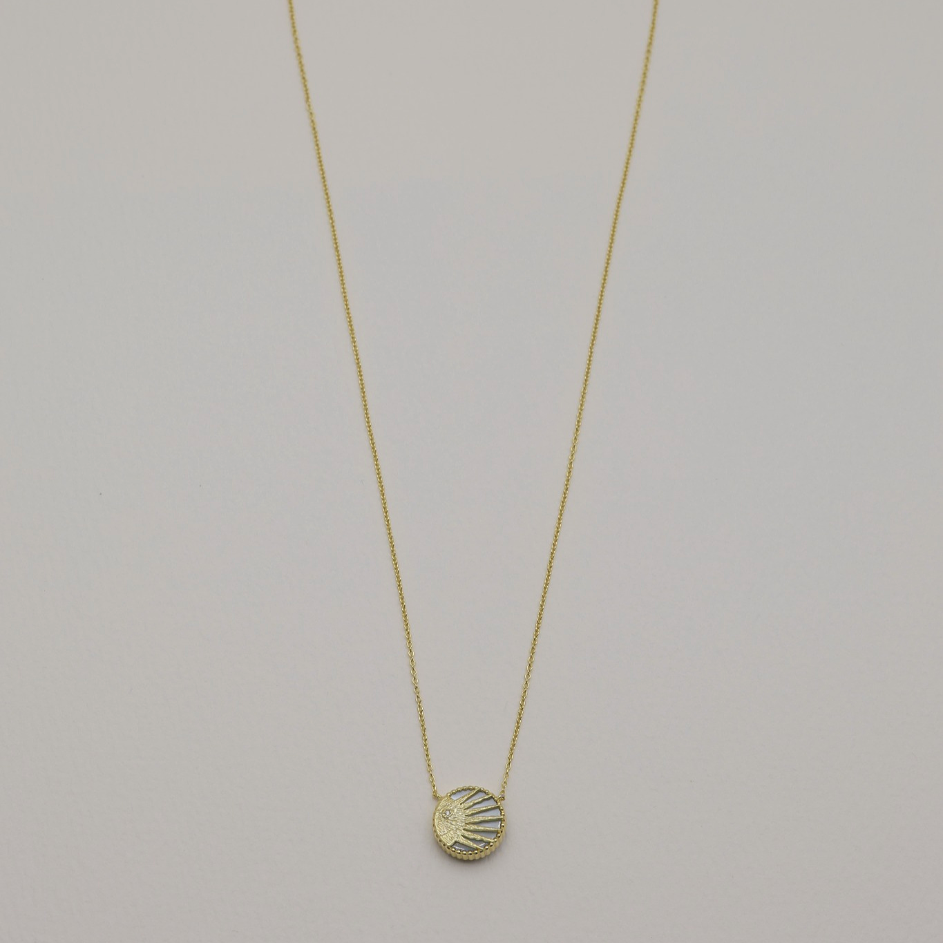 Full view of the necklace laid flat, showing the sun side of the pendant.