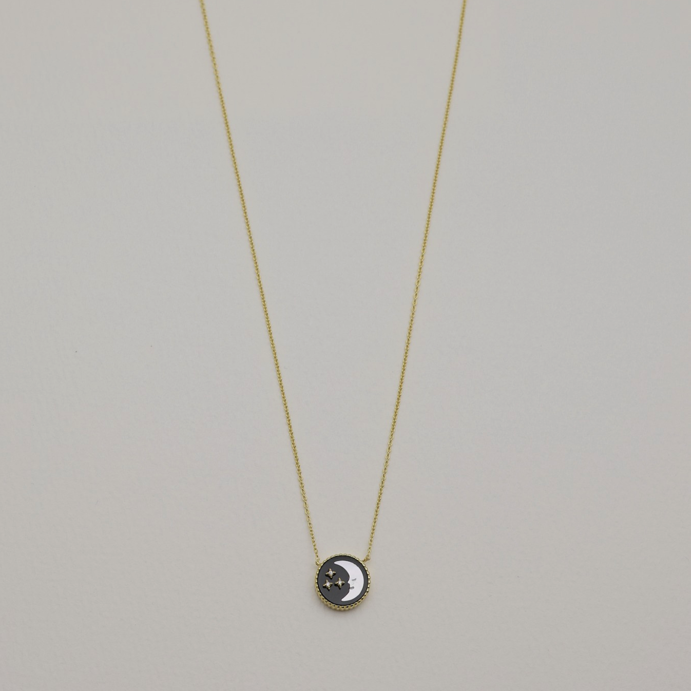 Full view of the necklace laid flat, showing the moon side of the circular pendant.