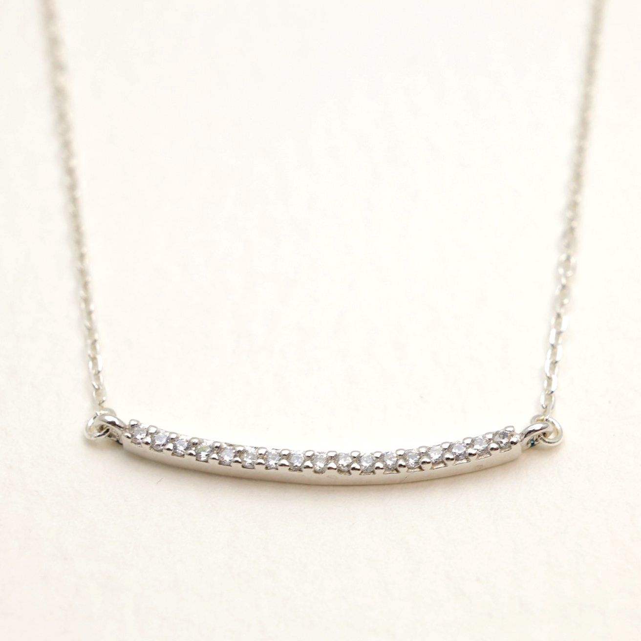 Close-up of curved bar pendant with cubic zirconia in sterling silver on fine chain