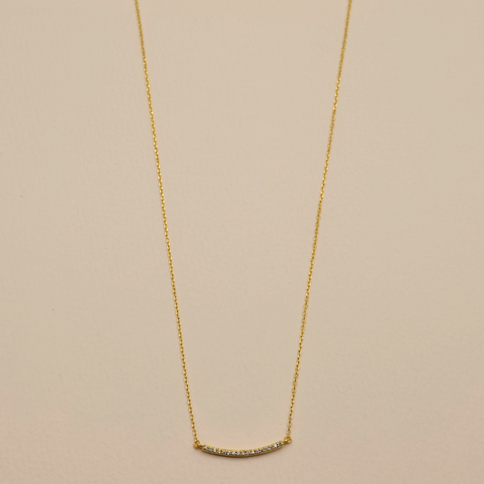 Flat lay of Clémence Bar Necklace in gold vermeil with cubic zirconia on cream background