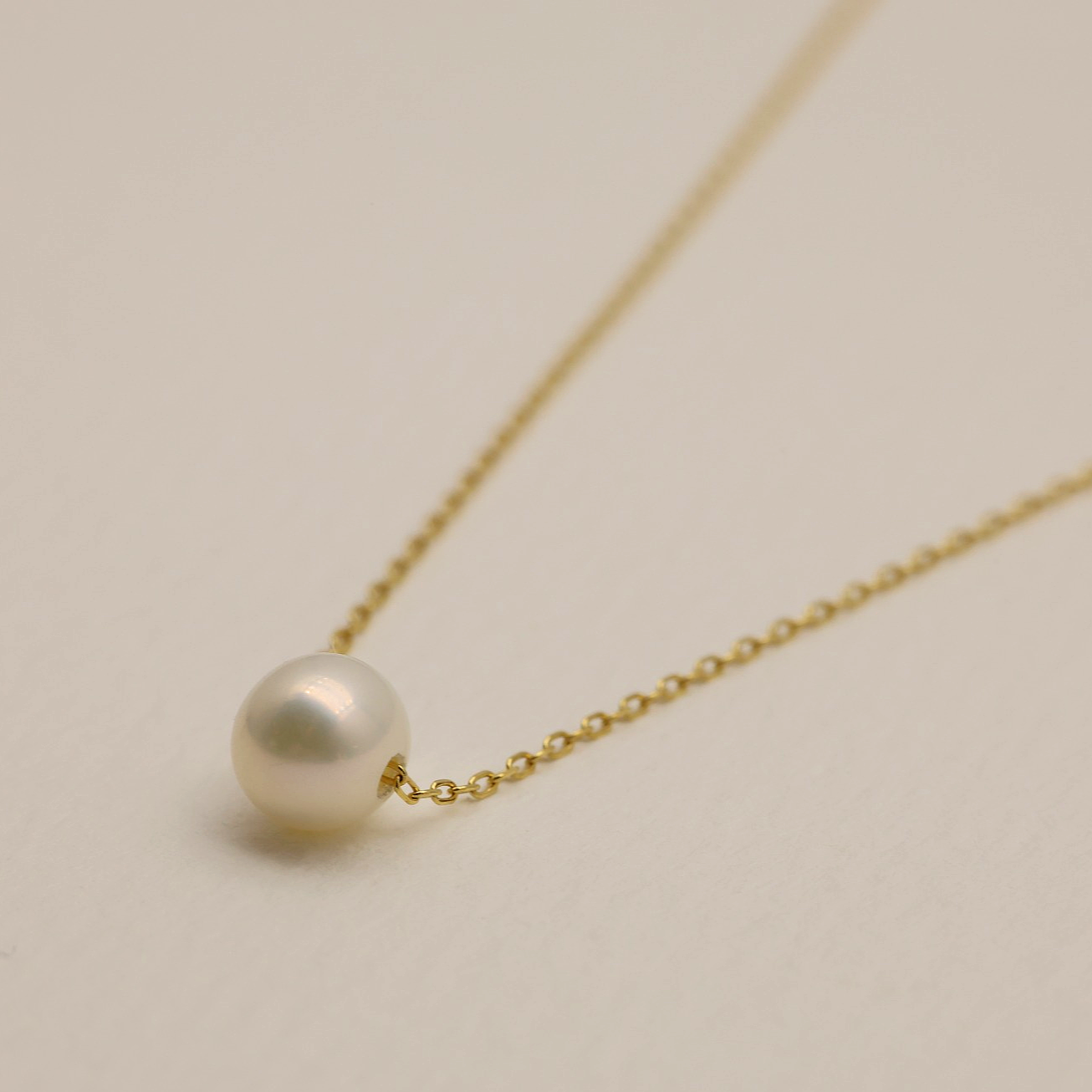 Angled flat-lay showing the pearl's soft glow on a gold vermeil chain