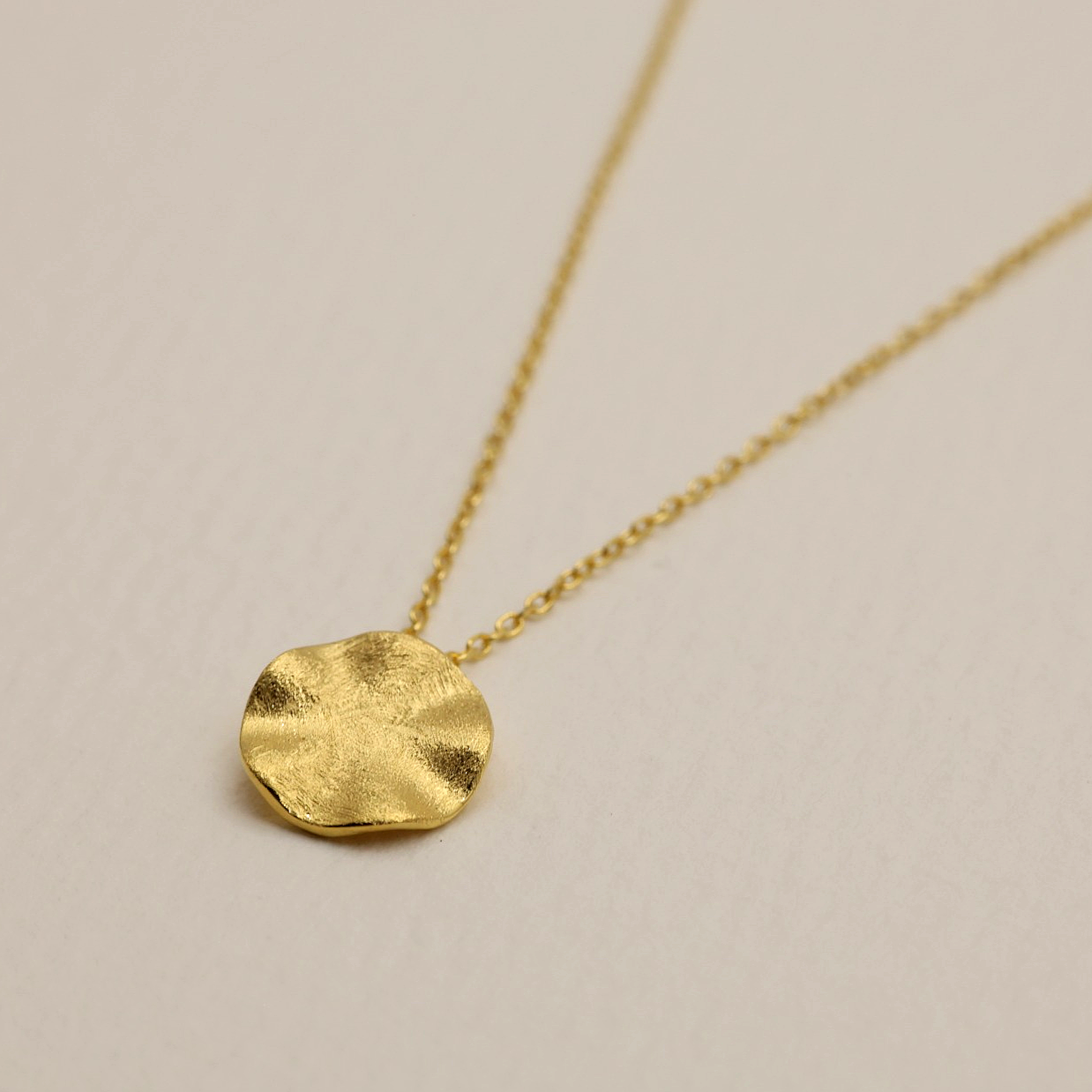 Close-up of the Éline Necklace in gold vermeil, showing the matte-textured round pendant on a fine chain