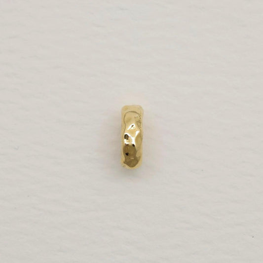 14K gold organic oval charm with hammered finish, photographed on soft white textured paper background