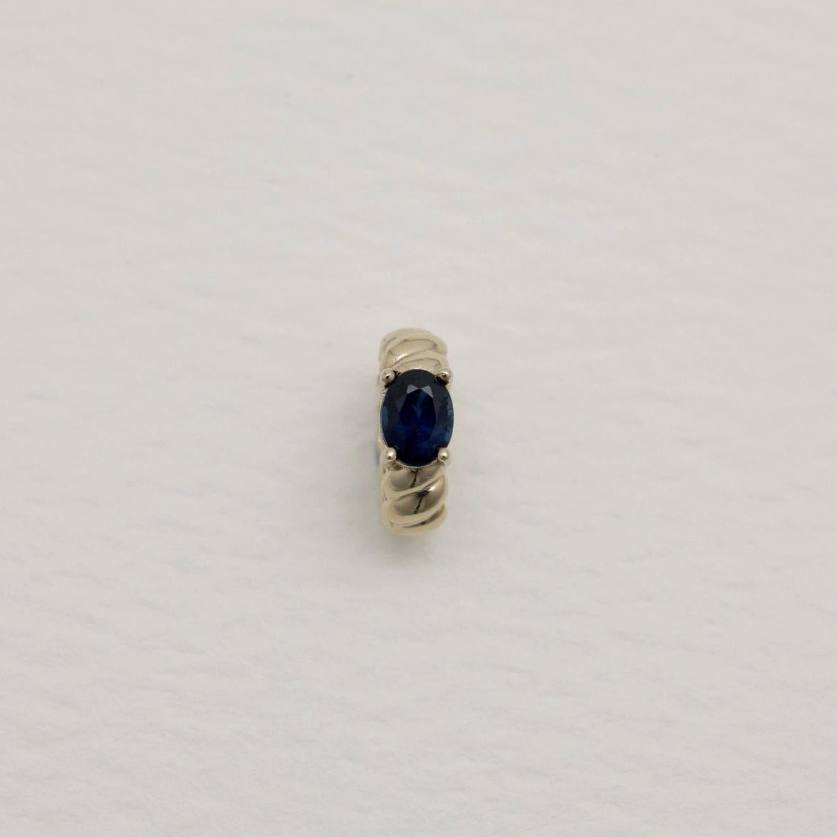 Gold ring with a blue gemstone on a light gray background