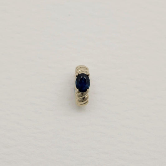 Gold ring with a blue gemstone on a light gray background