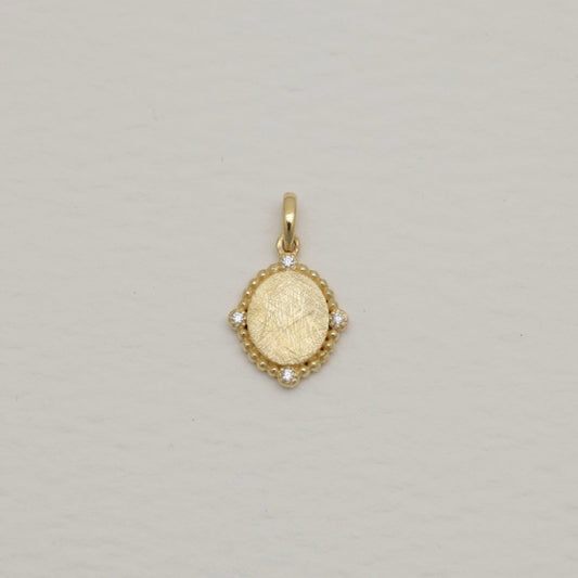 14K gold charm pendant with oval brushed center and four cubic zirconia, surrounded by beaded details.