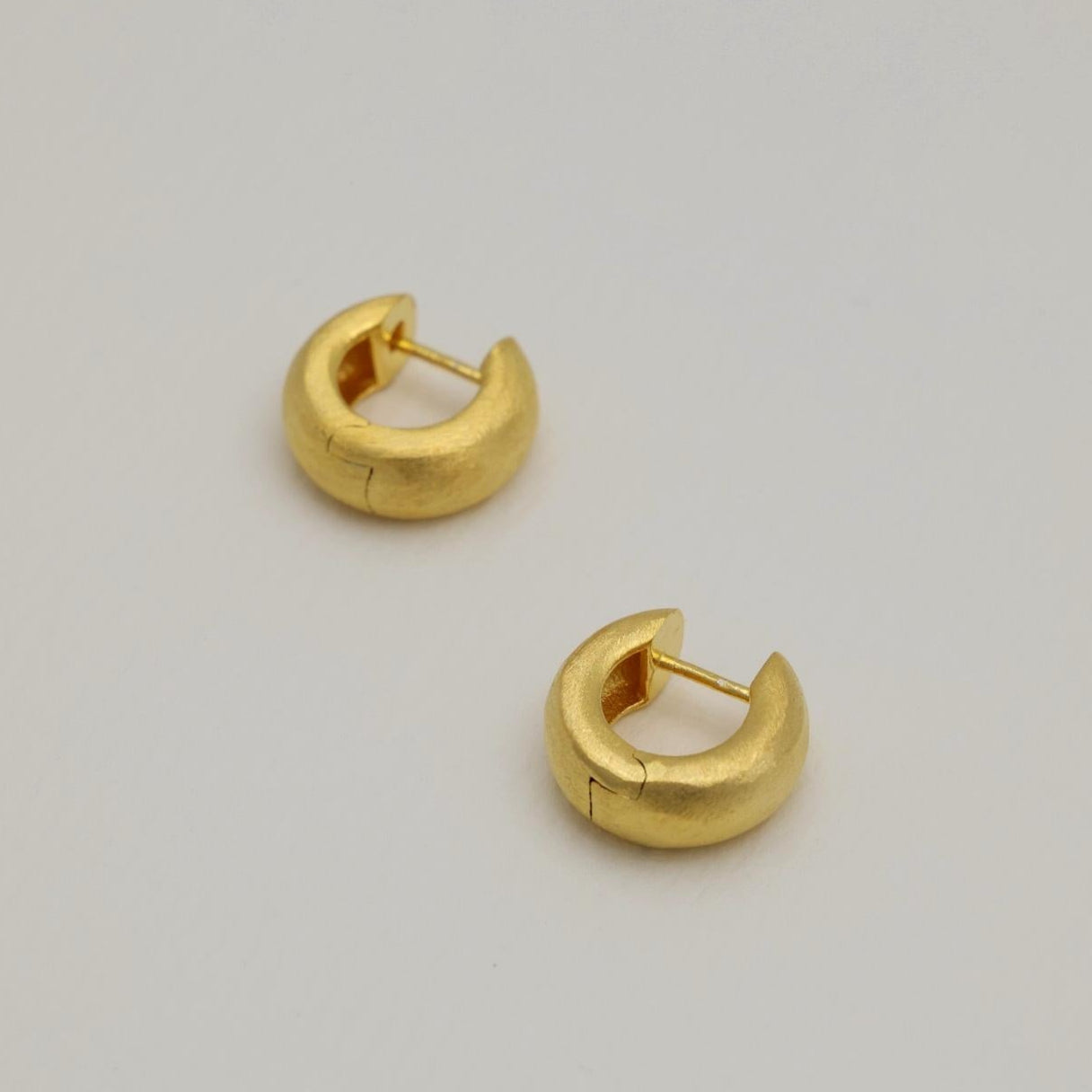 Pair of matte brushed mini gold vermeil hoop earrings on white background.