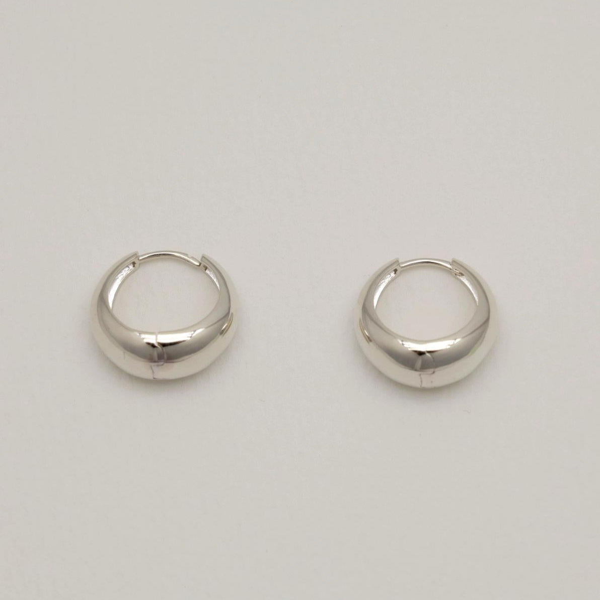 Pair of silver hoop earrings on a light gray background