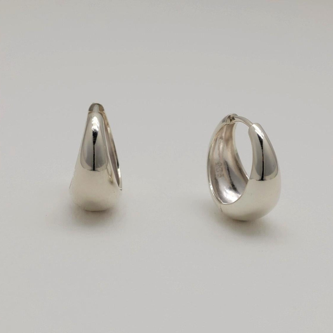 Two silver hoop earrings on a light gray background