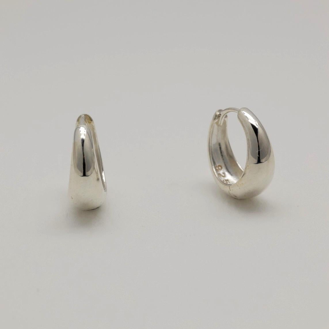 Two silver hoop earrings on a light gray background