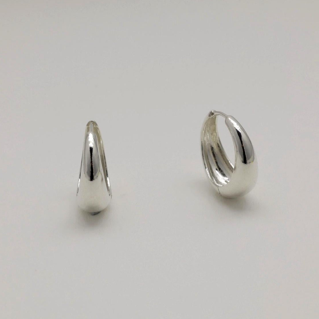 Two silver hoop earrings on a light gray background