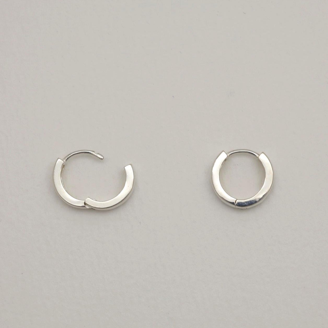 Two silver hoop earrings on a light gray background