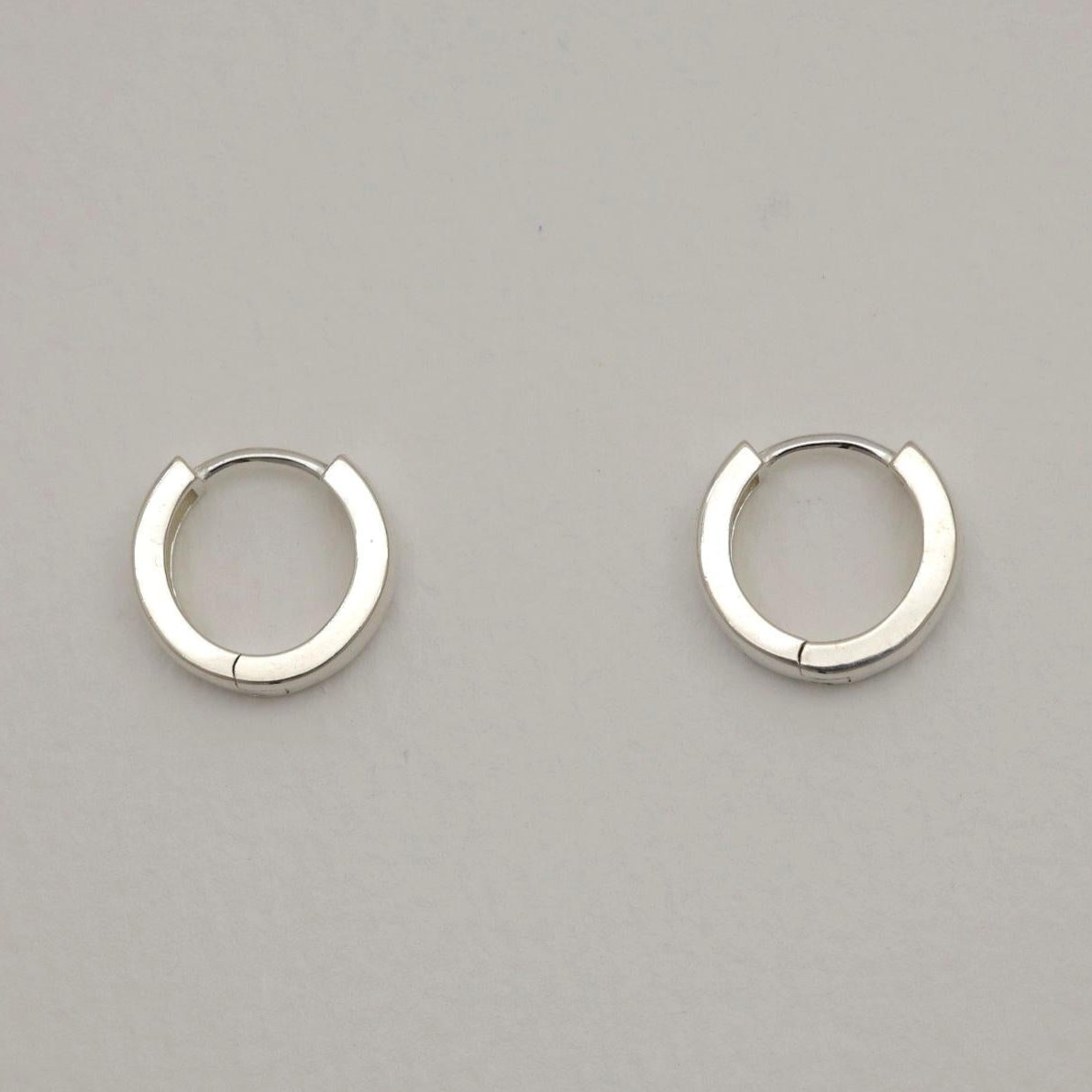 Pair of silver hoop earrings on a gray background