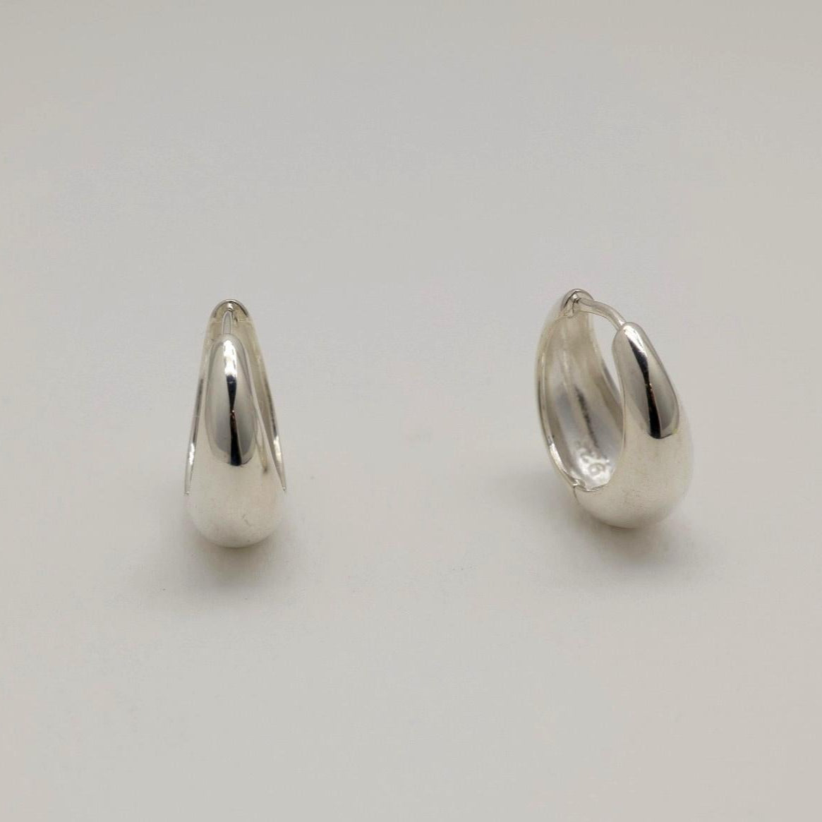 Two silver hoop earrings on a light gray background