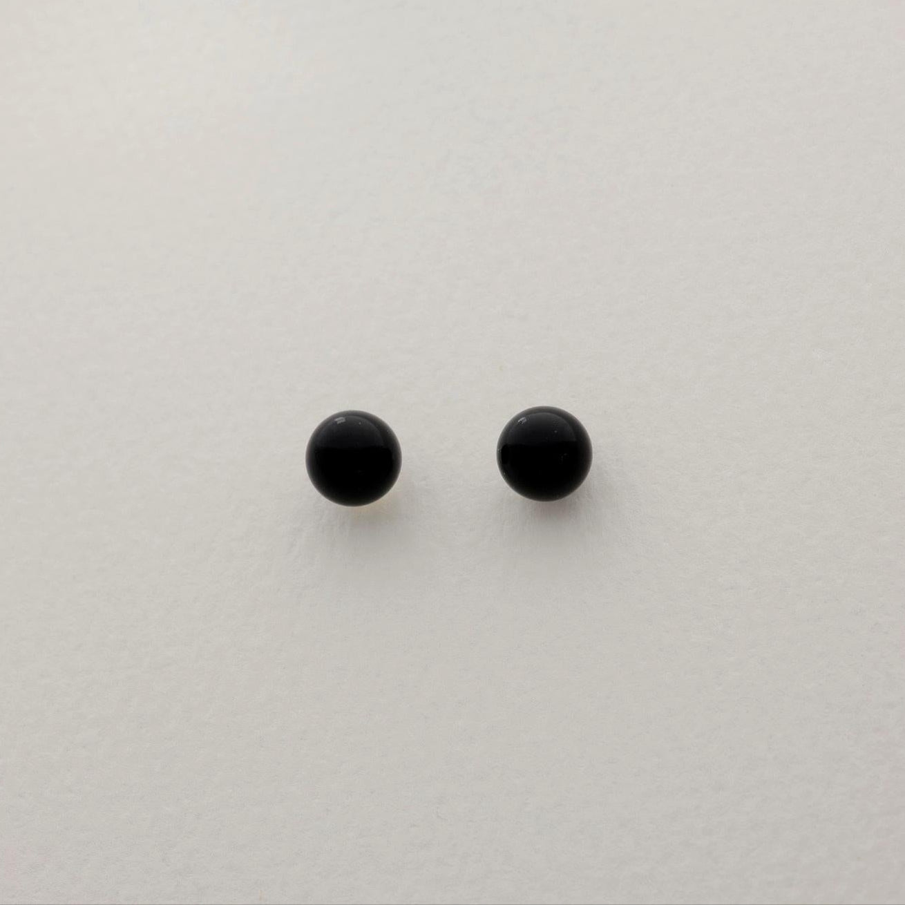 A pair of round black onyx stud earrings on a soft white background