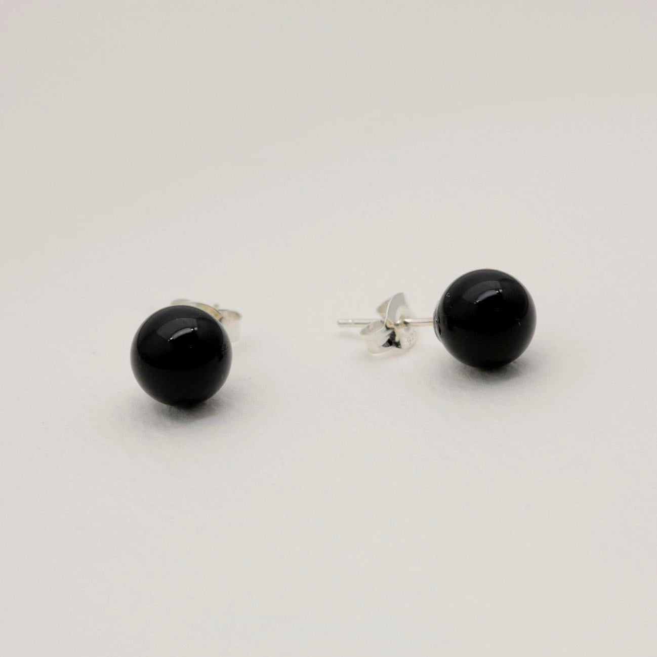 A pair of round black onyx stud earrings on a soft white background