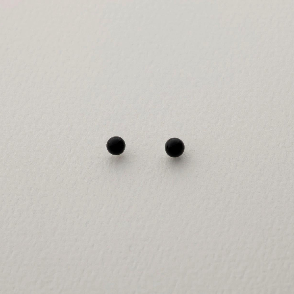 A pair of round black onyx stud earrings on a soft white background