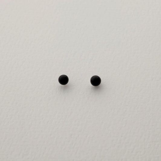 A pair of round black onyx stud earrings on a soft white background