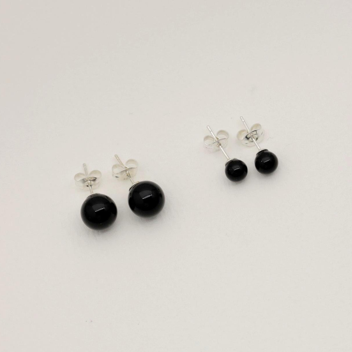 A pair of round black onyx stud earrings on a soft white background