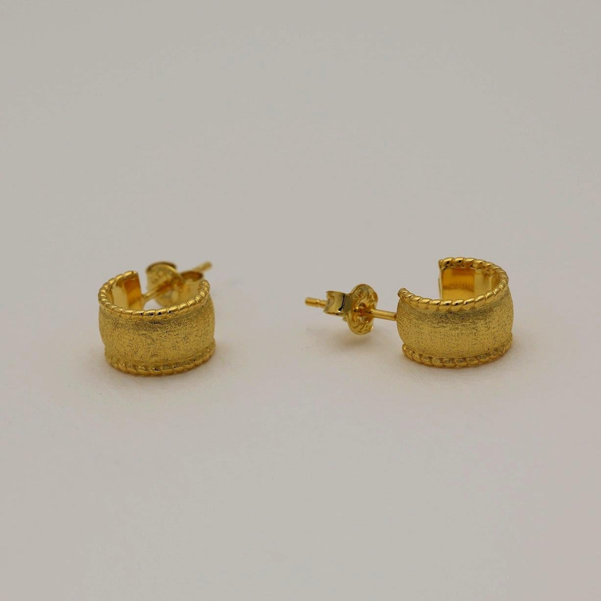 Gold vermeil textured dome huggie earrings with a softly brushed finish, shown from front and side angles on a neutral background.