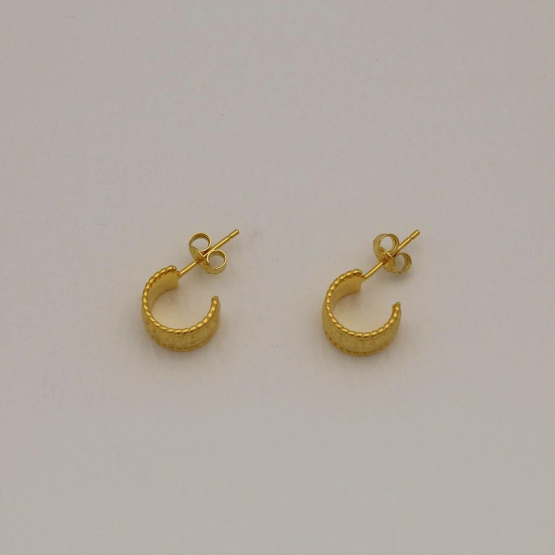 Gold vermeil textured dome huggie earrings with a softly brushed finish, shown from front and side angles on a neutral background.