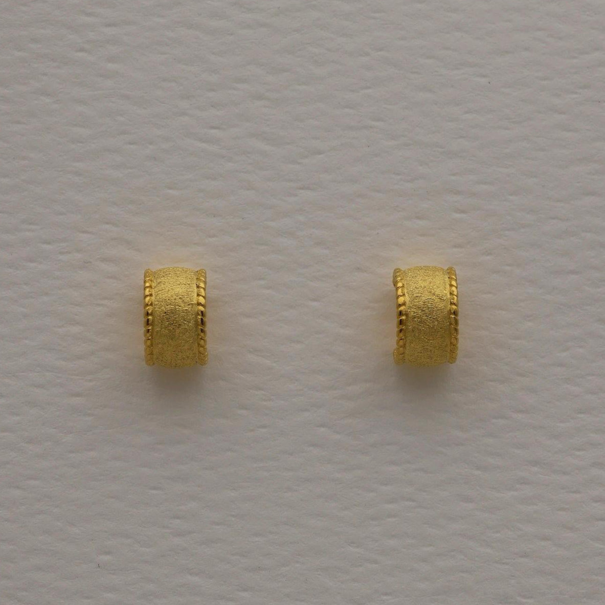 Gold vermeil textured dome huggie earrings with a softly brushed finish, shown from front and side angles on a neutral background.