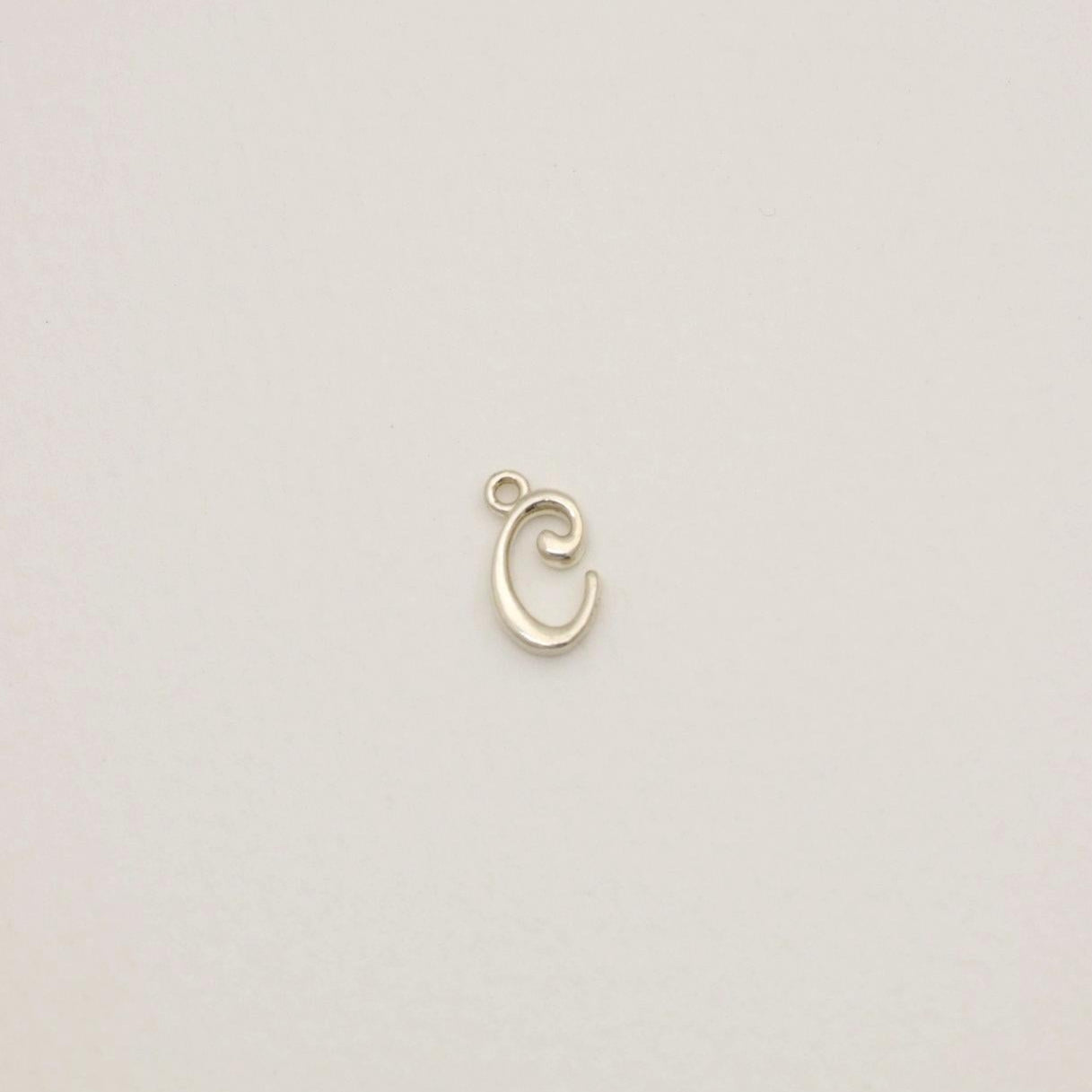 Sterling silver initial pendant with softly polished finish, photographed on neutral background.