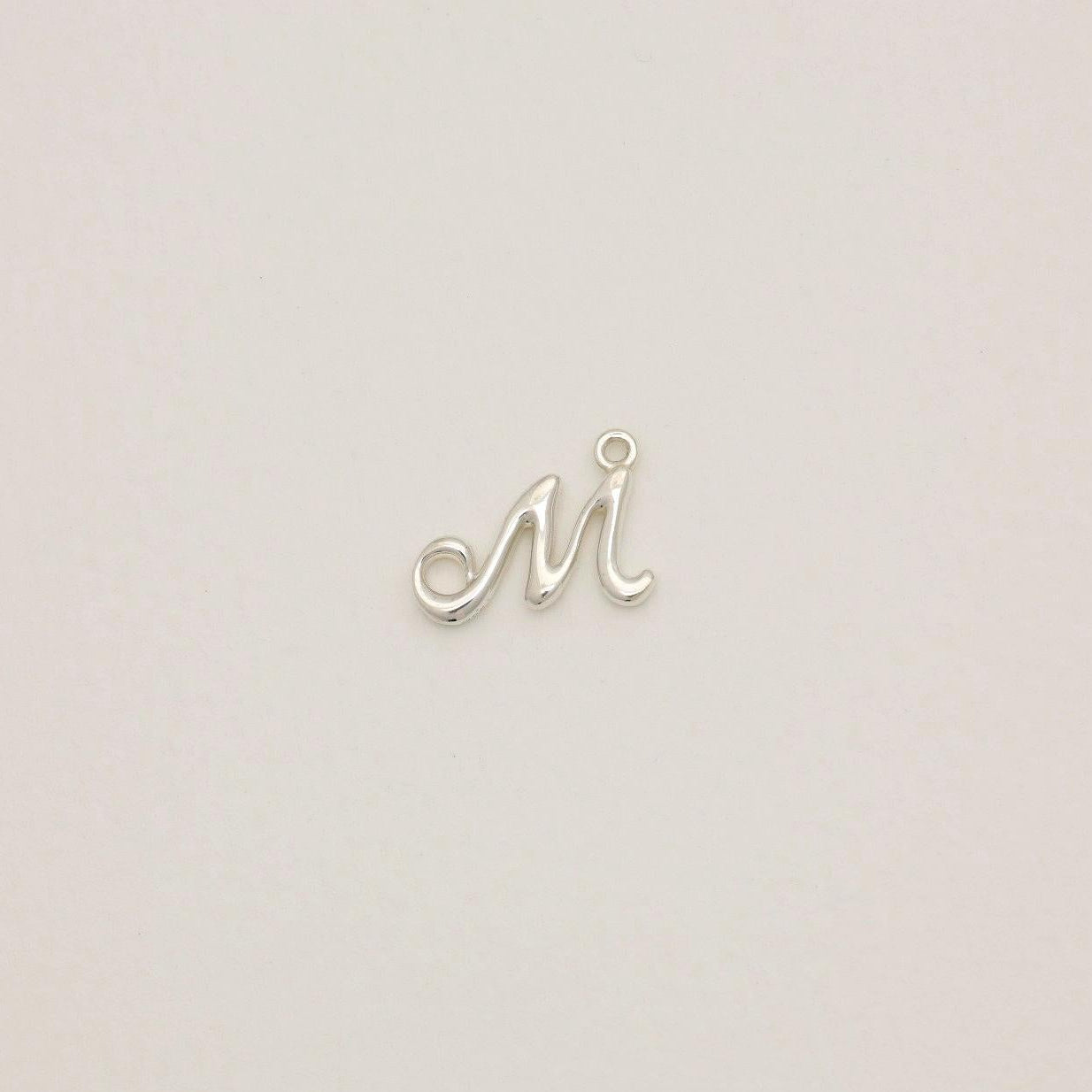 Sterling silver initial pendant with softly polished finish, photographed on neutral background.
