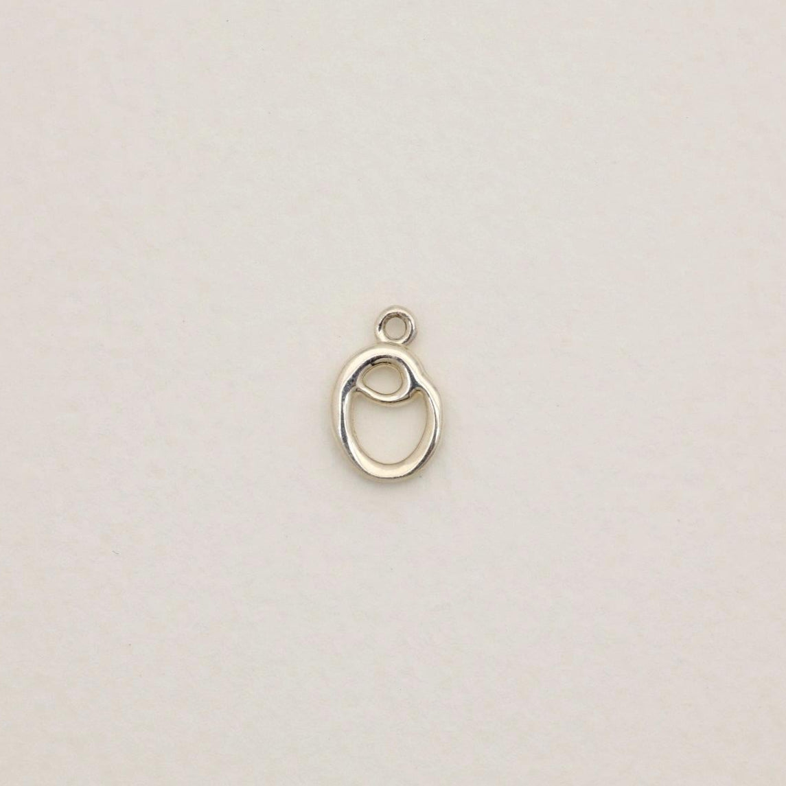 Sterling silver initial pendant with softly polished finish, photographed on neutral background.