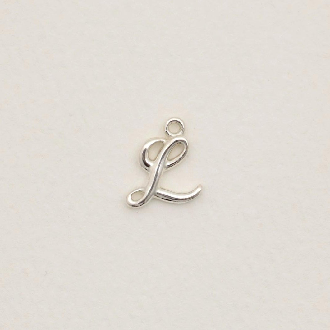Sterling silver initial pendant with softly polished finish, photographed on neutral background.