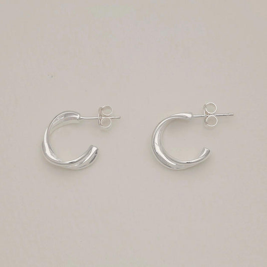 Pair of folded design sterling silver stud earrings on light background, soft polished finish