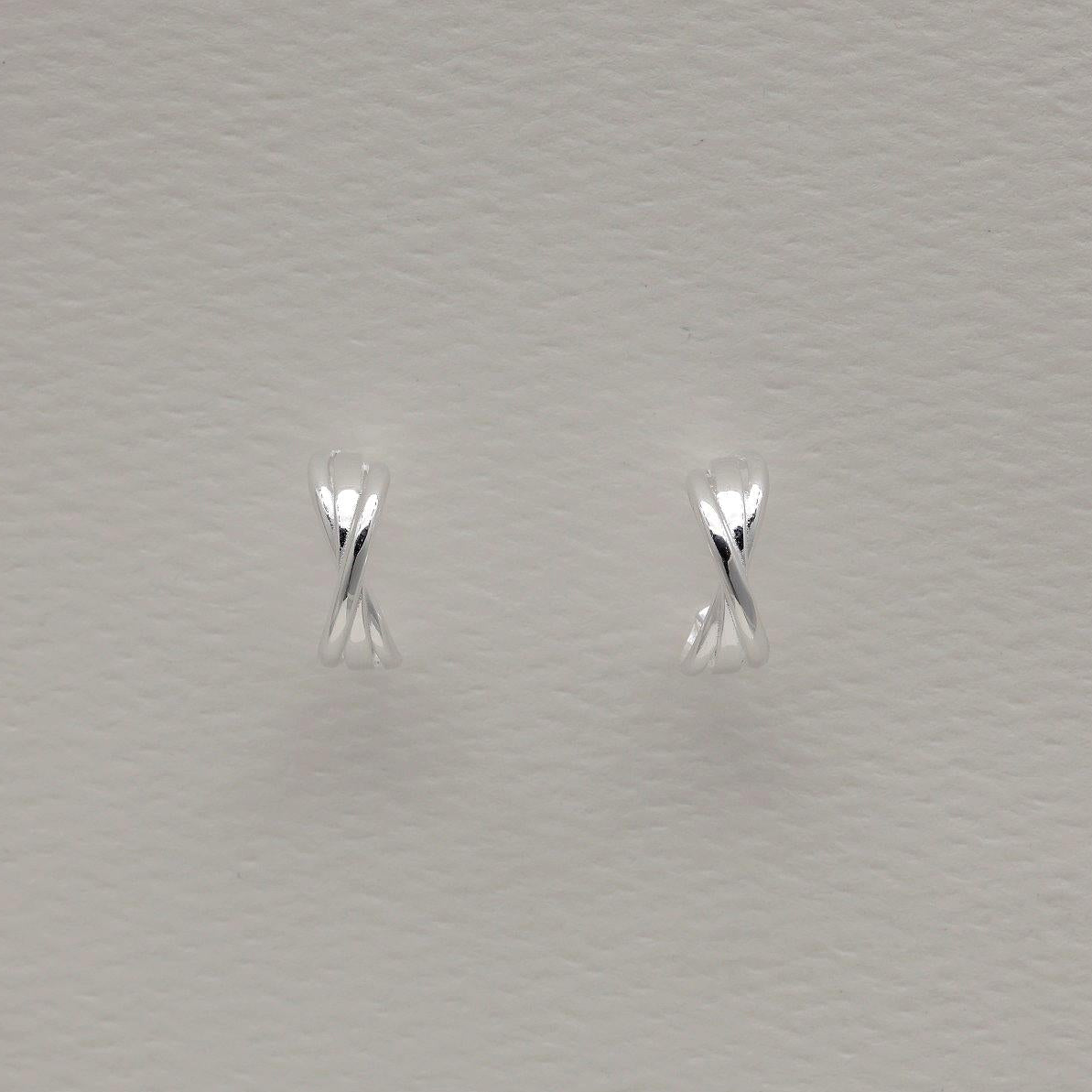 Pair of folded design sterling silver stud earrings on light background, soft polished finish