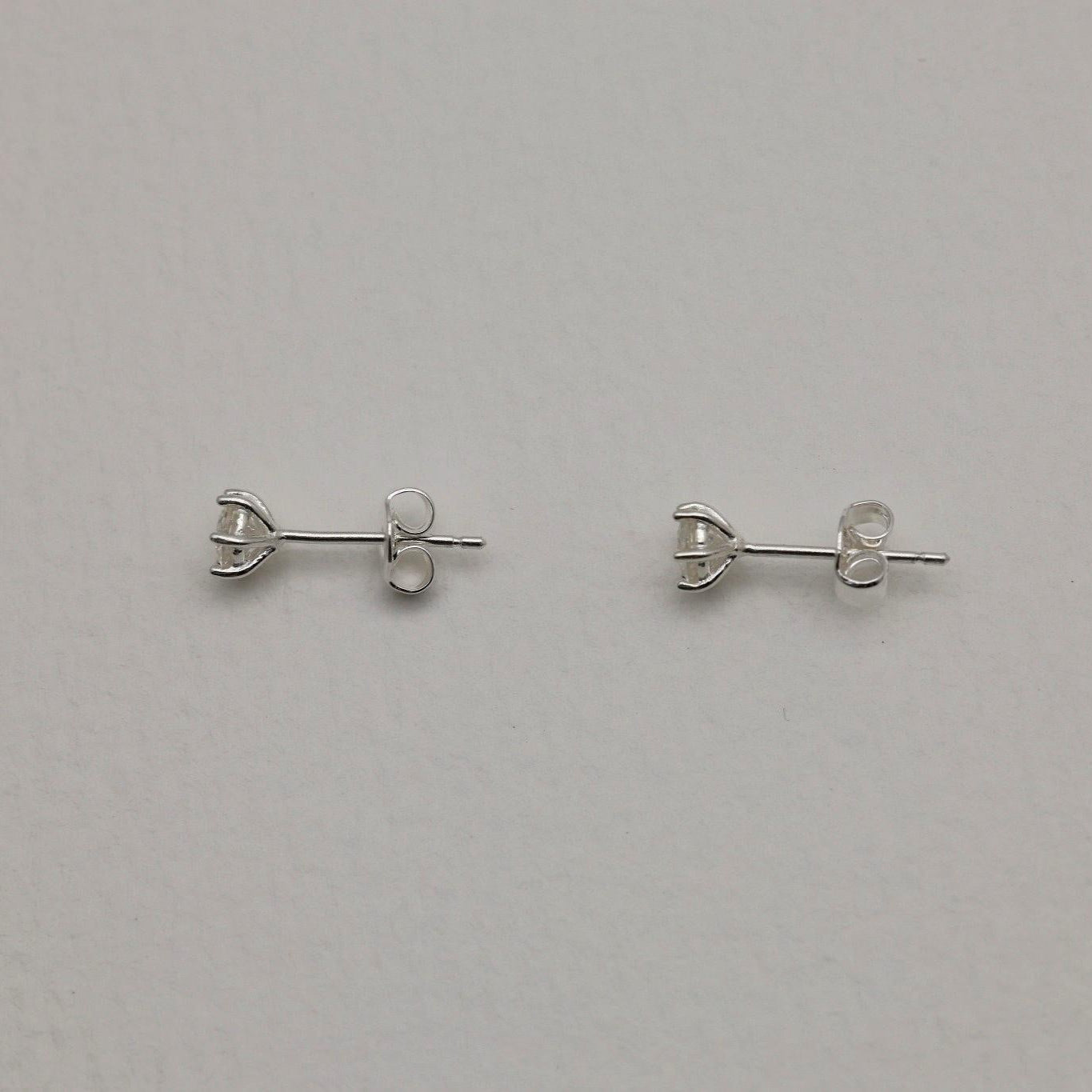Front and side views of the Loane Moissanite Stud Earrings in Sterling Silver, showing six-prong setting and butterfly backings.