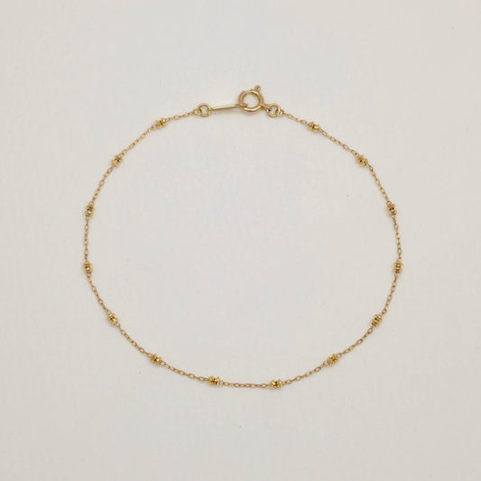 Delicate 10K gold bracelet with polished bead details, 18cm in length, laid flat in a circular shape on a light background.