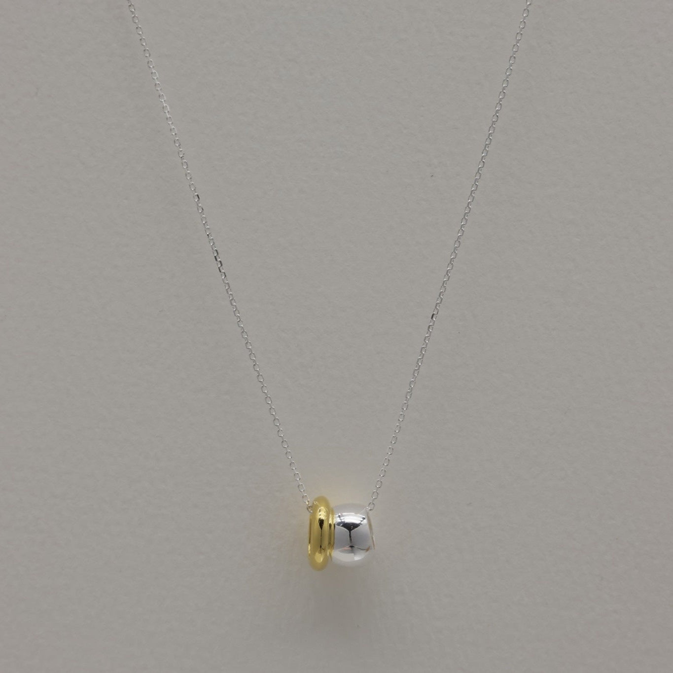 Front view of the Léontine Necklace styled in a soft curve, highlighting the contrast between the gold and silver tones.