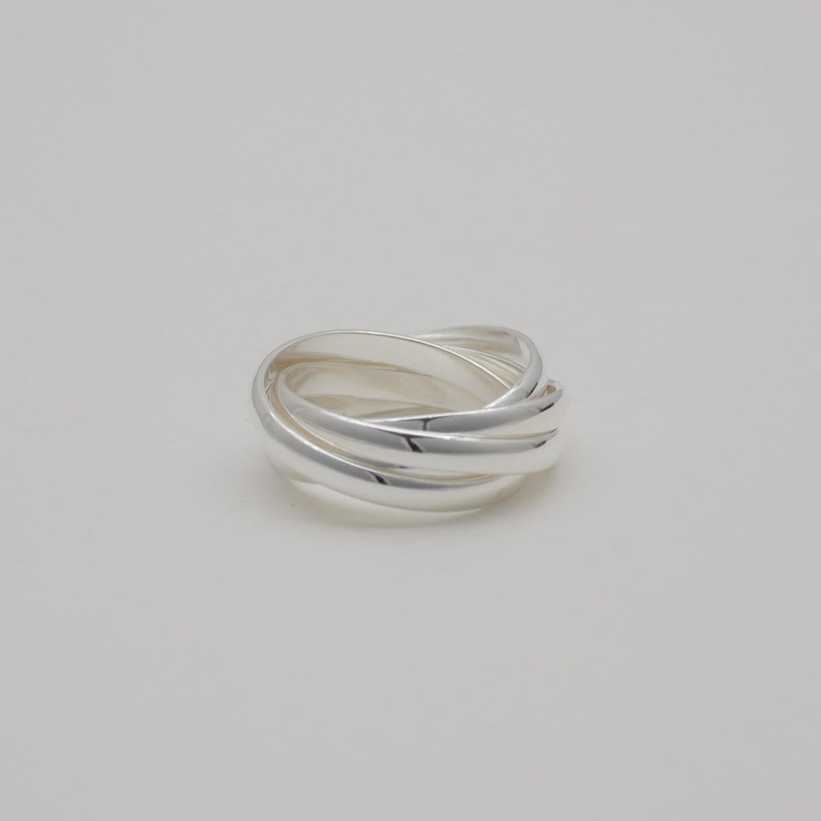 Three interlocking polished sterling silver bands forming a trinity ring

