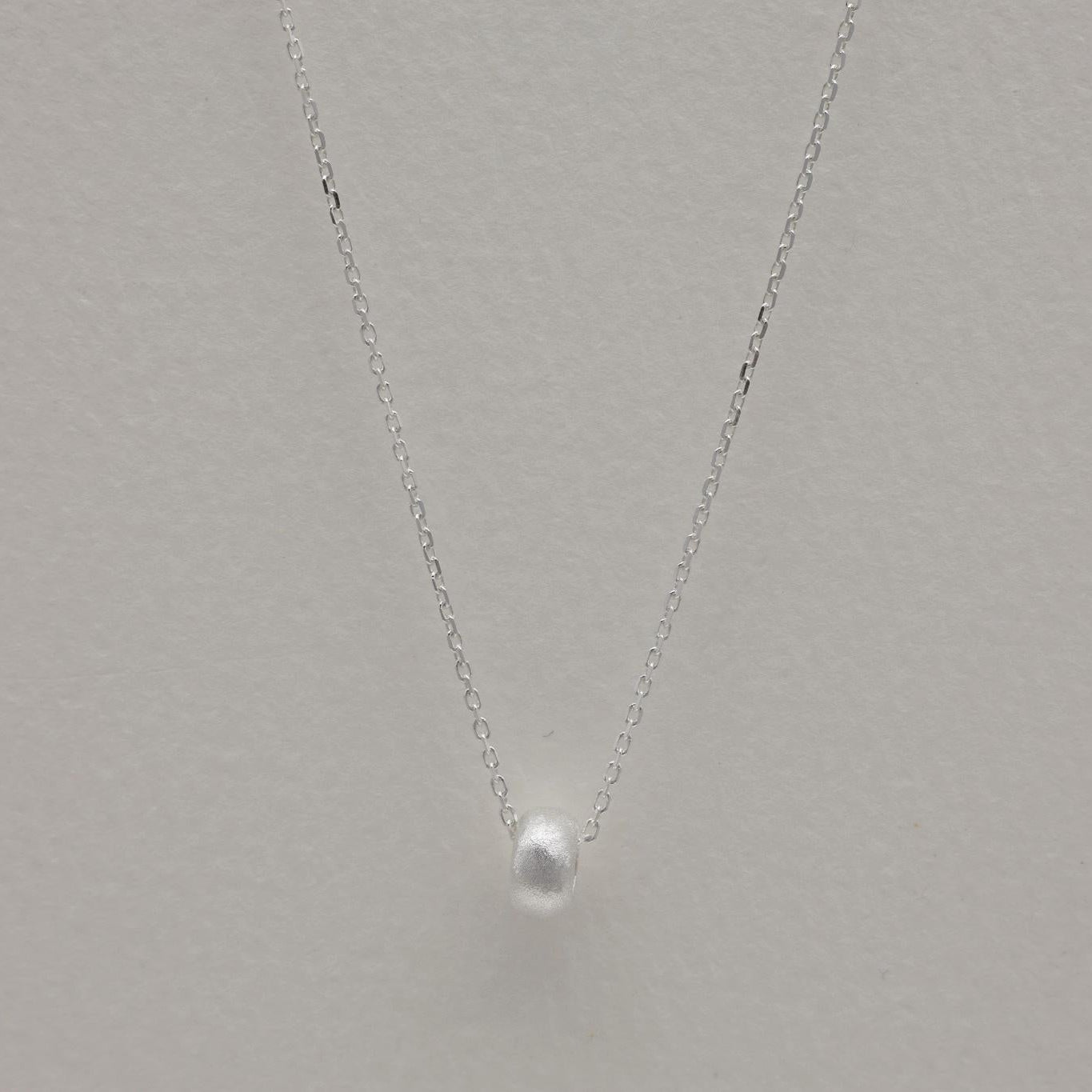 Full view of the Noémie Necklace styled in a gentle curve with soft lighting and clean background.
